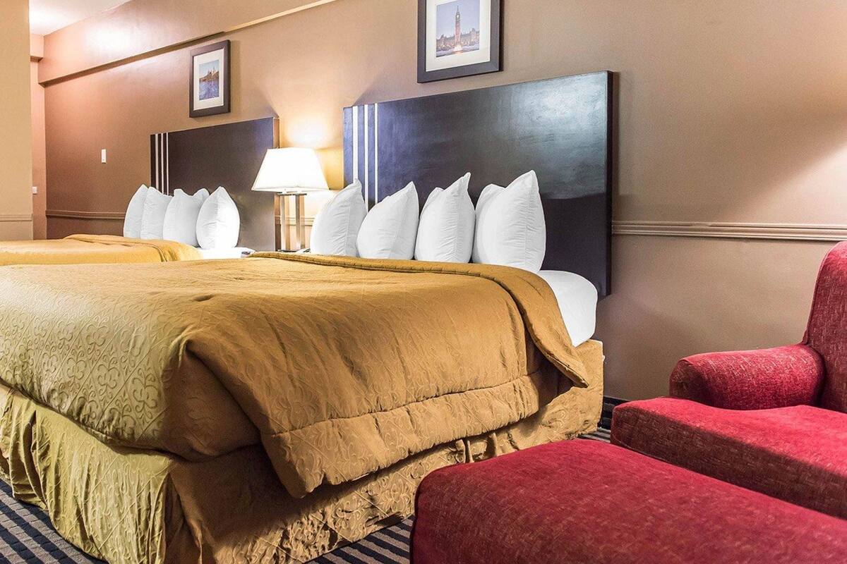 Een hotelkamer met een groot bed, een bureau, een stoel en twee ingelijste foto's aan de muur.
