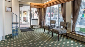 Un hall d’hôtel doté d’un tapis à motifs, d’un escalier et d’un espace salon avec des fauteuils à motifs.