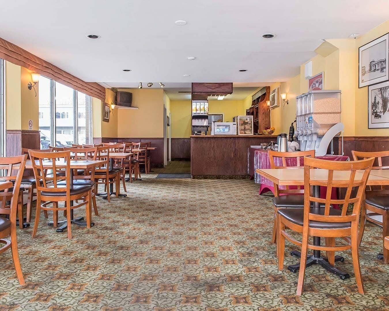 A restaurant with wooden tables and chairs, a patterned carpet, and a counter with a cash register.