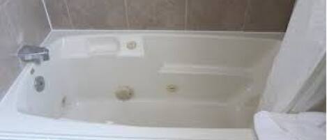 Una bañera con cortina de ducha, un cabezal de ducha manual y un panel de control.