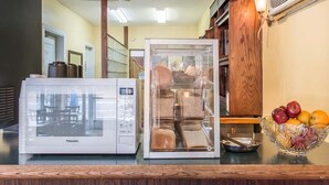 Une cuisine équipée d’un four à micro-ondes, d’un garde-pain et d’un panier à fruits.