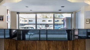Un espace d  ’accueil avec une cloison en verre, un comptoir en bois et des trophées encadrés accrochés au mur.
