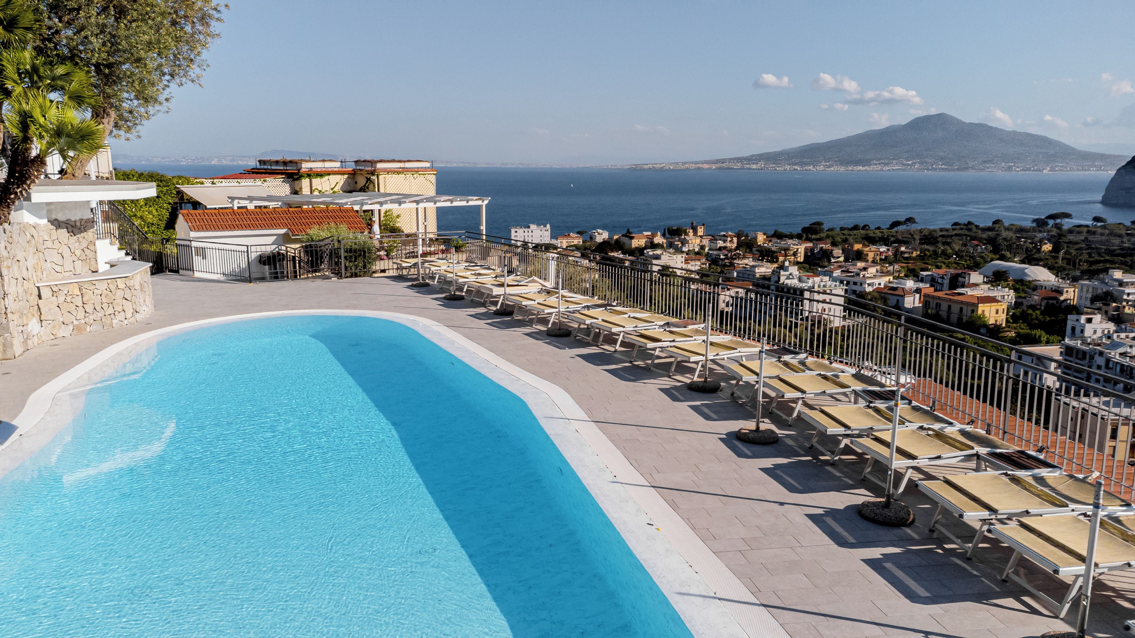A swimming pool with a view of the sea and a cityscape in the background.