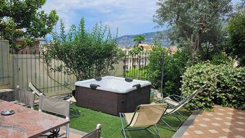Un patio trasero con un jacuzzi, una mesa y sillas.