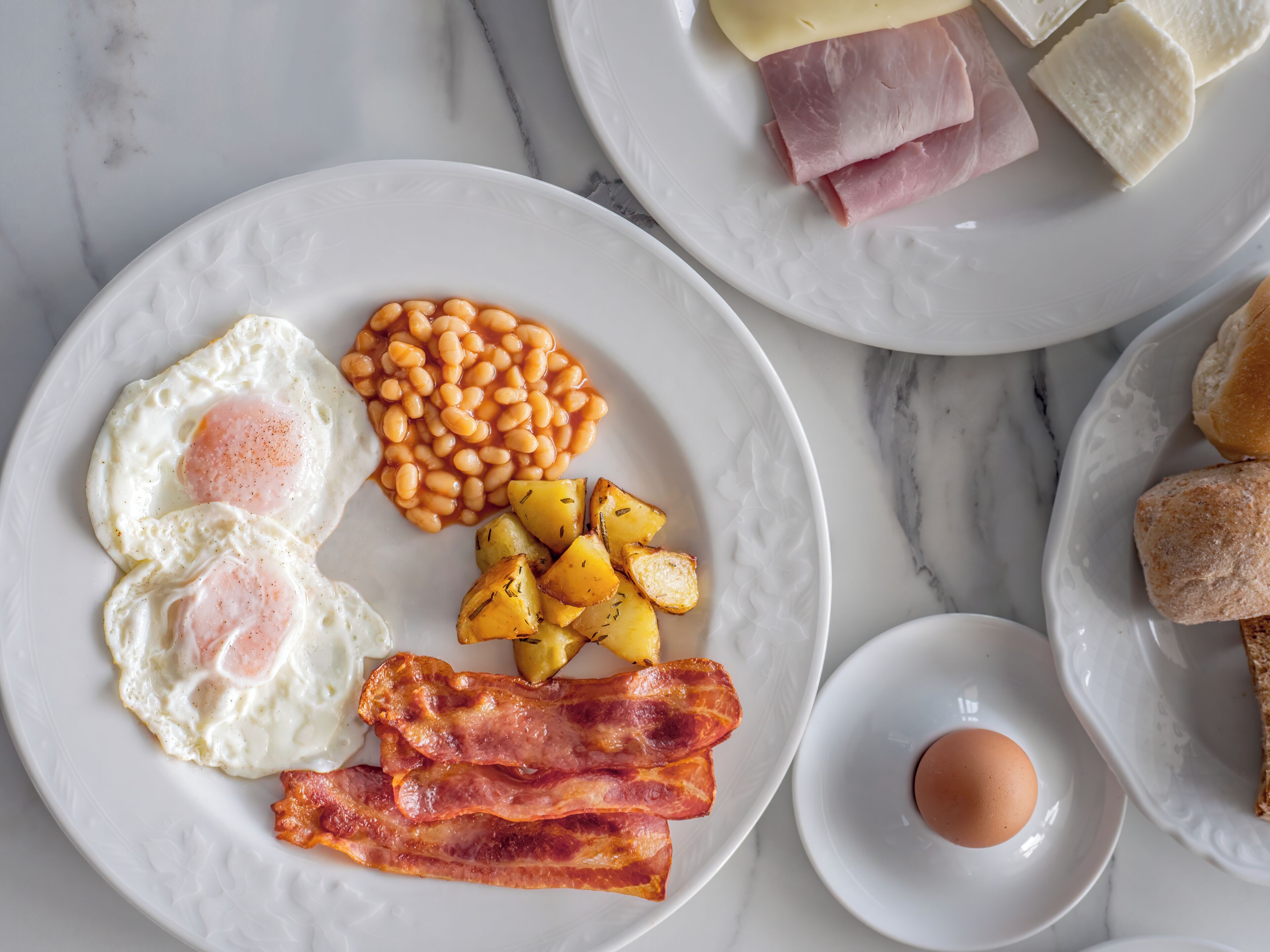 Une assiette de petit-déjeuner comprenant des œufs, des haricots, du bacon et des pommes de terre.