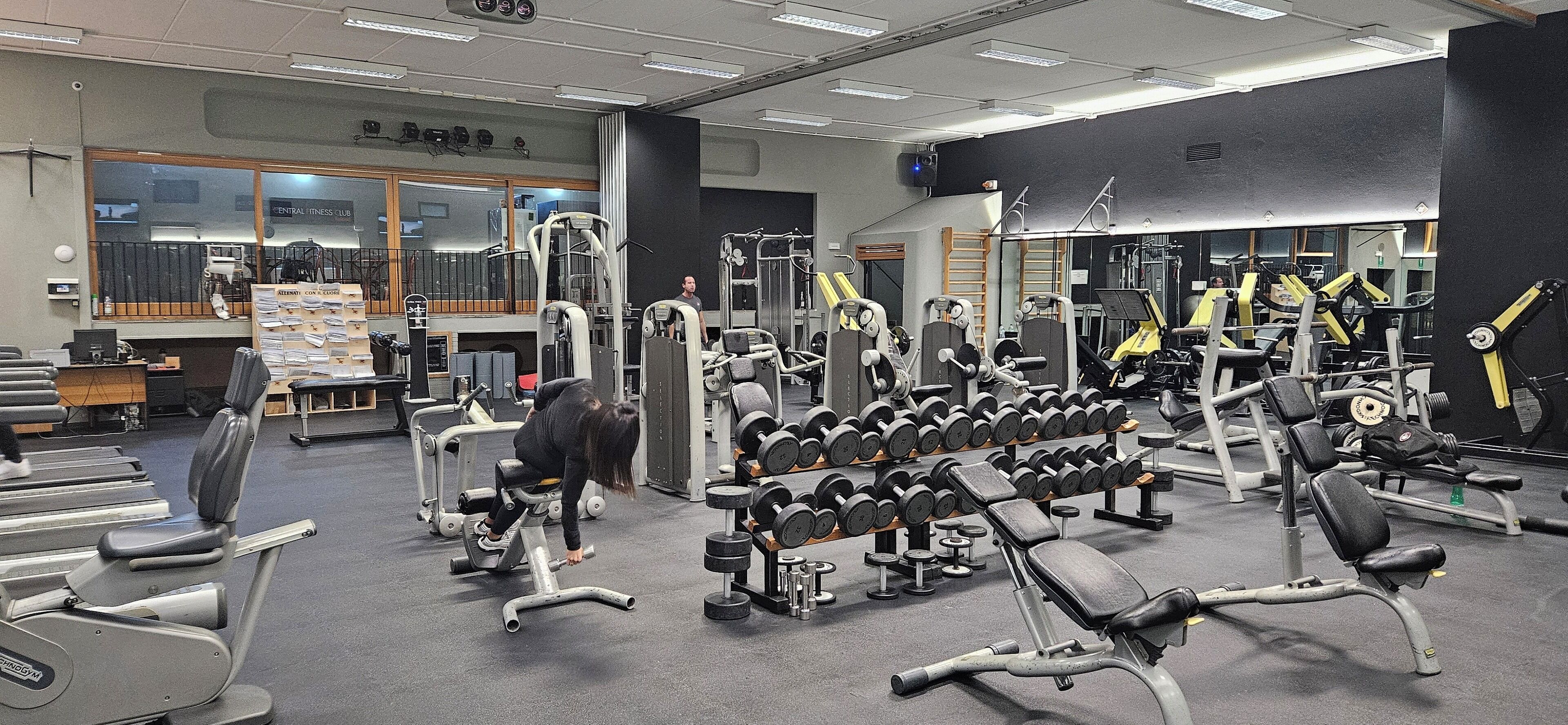 A gym with various exercise equipment, including treadmills, dumbbells, and weight machines.