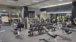 Un gimnasio con diverso equipo de ejercicio, incluyendo cintas de correr, mancuernas y máquinas de pesas.