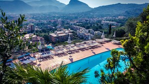 Un resort con piscina, sillas de descanso y vistas a la ciudad y las montañas.