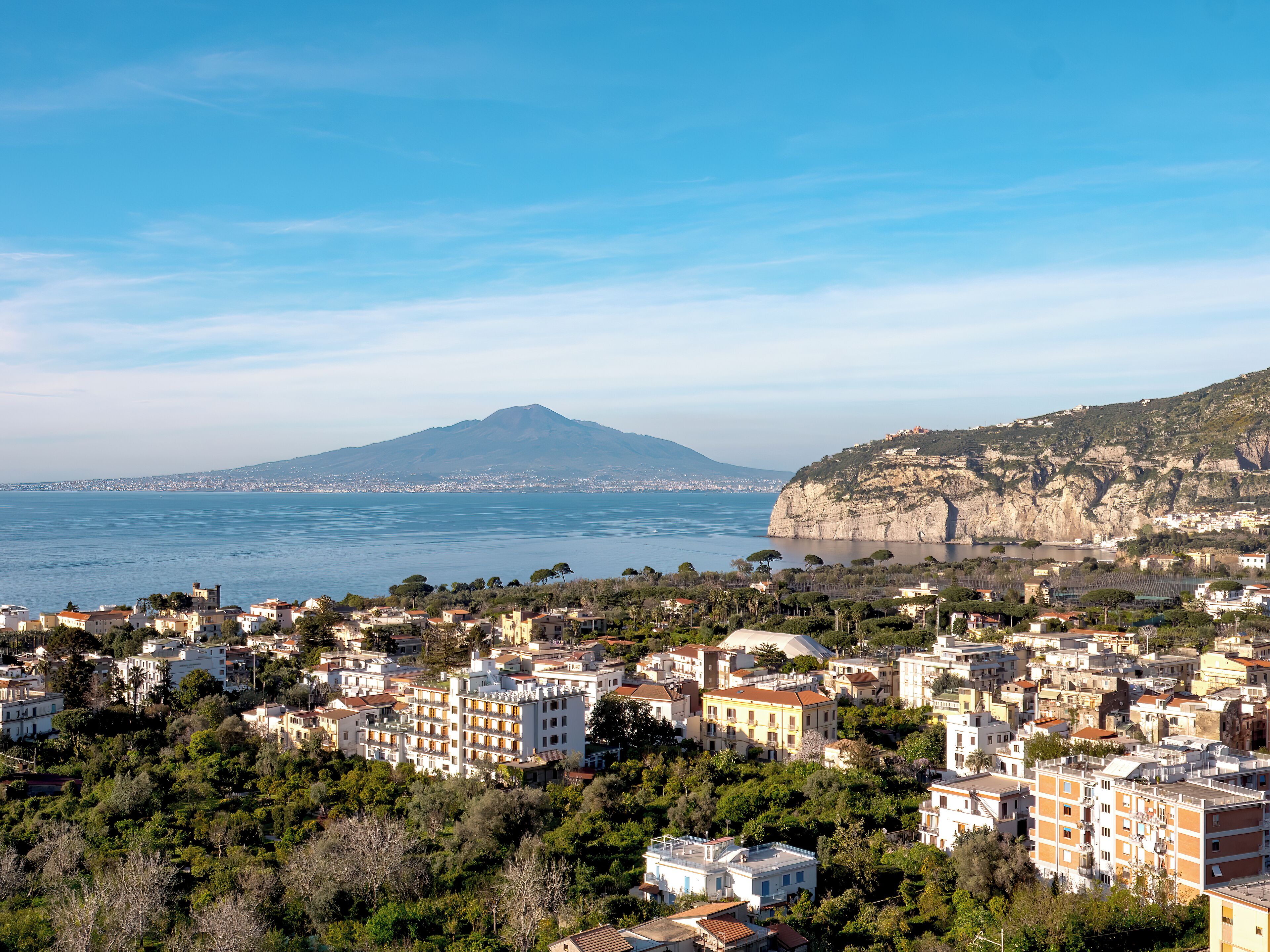 A coastal town with buildings, a mountain, and the sea.