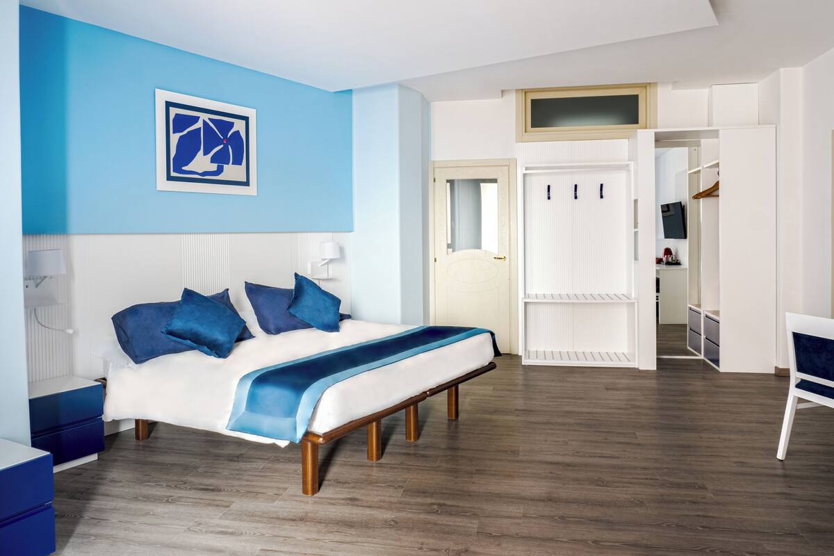 A modern bedroom with a bed, bedside tables, a wardrobe, and a desk.