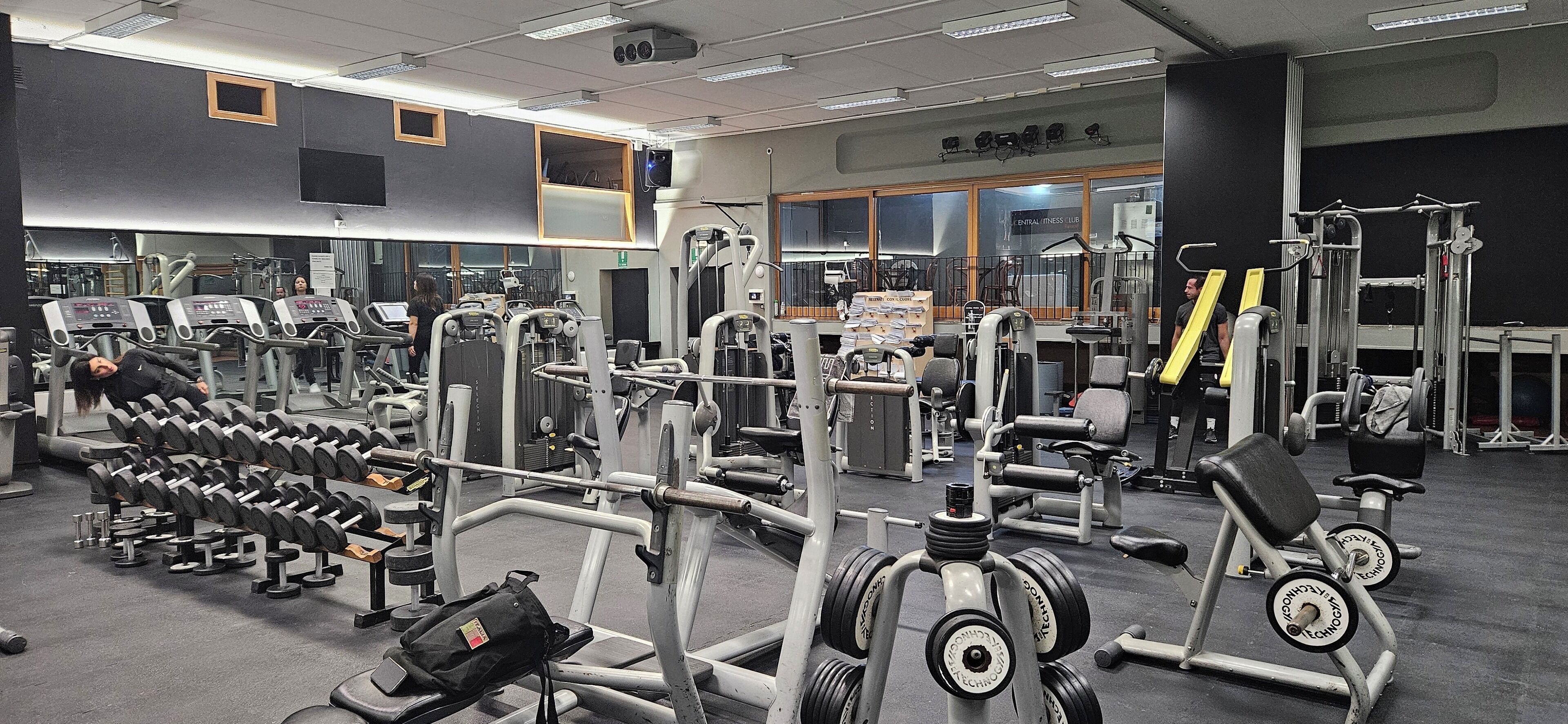 Une salle de sport équipée de divers appareils d’entraînement, notamment des tapis de course, des appareils de musculation et des poids libres.