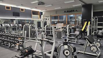 A gym with various exercise equipment, including treadmills, weight machines, and free weights.