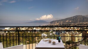 Un balcón con mesa lista para comer, con vistas a un paisaje urbano y una montaña al fondo.
