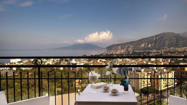 A balcony with a table set for dining, overlooking a cityscape with a mountain in the distance. - Cristina Hotel (Sant'Agnello)
