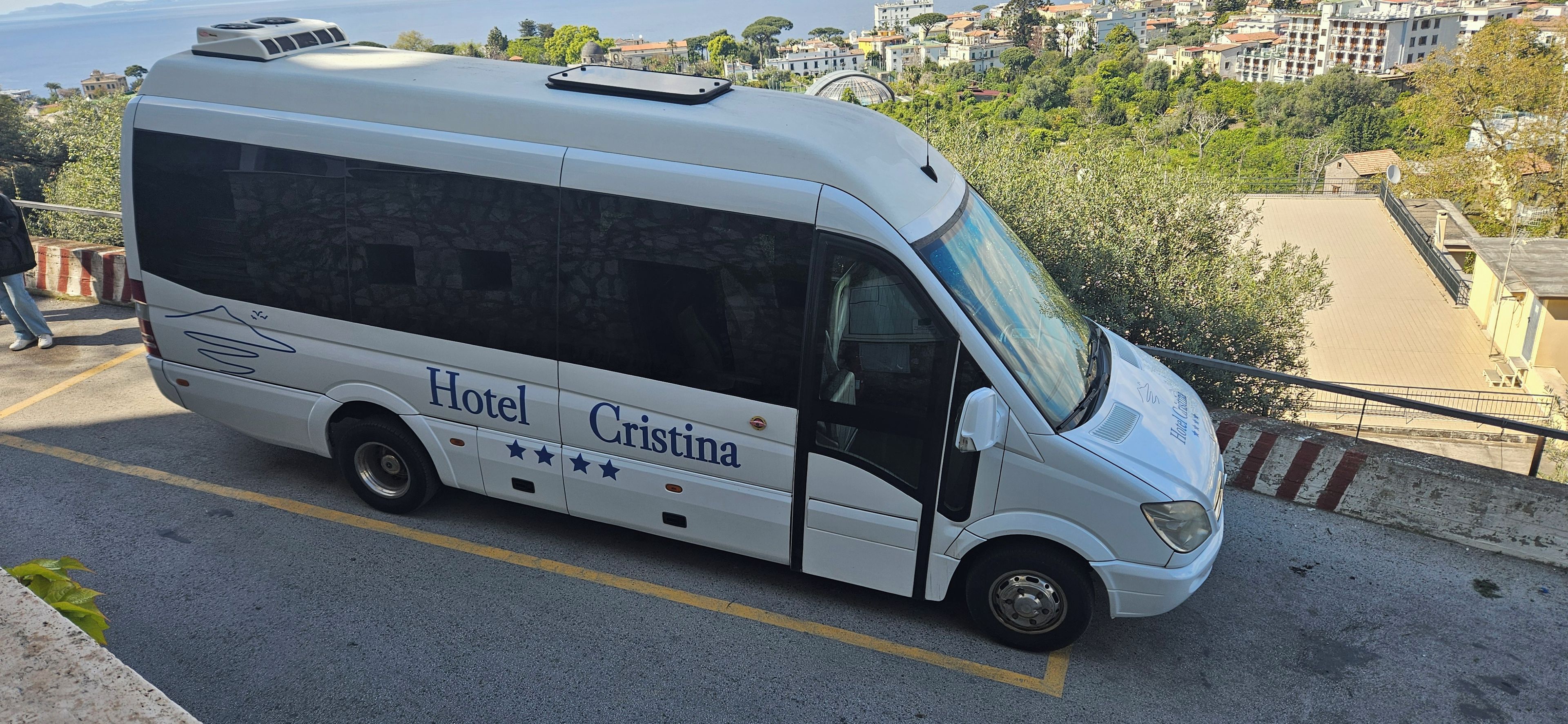 A white bus with 'Hotel Cristina' branding parked on a road.