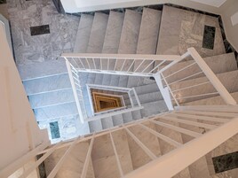A spiral staircase with white railings and marble steps.