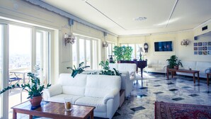 Un salón amplio con un sofá blanco, una mesa de centro y un ventanal con vistas a la ciudad.
