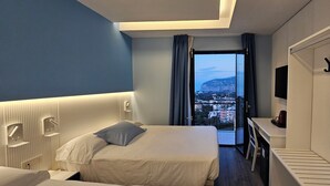 Una habitación de hotel con cama, escritorio, televisión y vistas a un paisaje urbano.