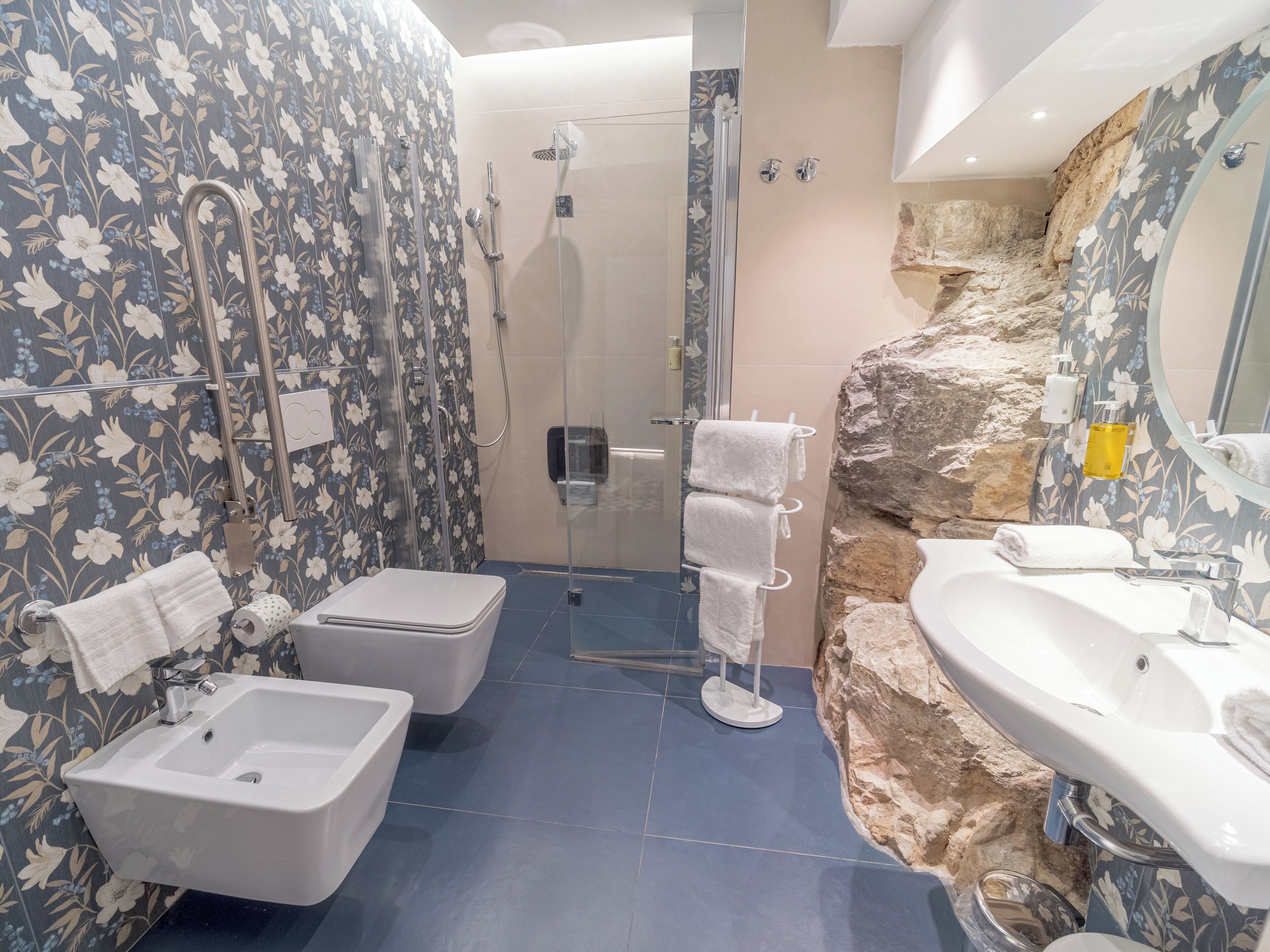 A bathroom with a shower, two sinks, and a toilet.