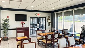 A restaurant with tables and chairs, a TV on the wall, and a door with an exit sign. - Quality Inn & Suites Cincinnati Downtown Area (Cincinnati)