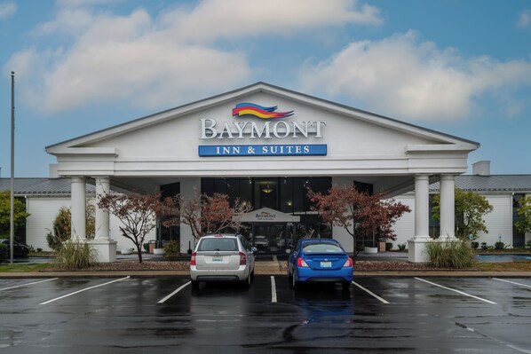 A Baymont Inn & Suites with a white facade, two parking spaces, and a clear sky.