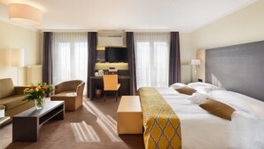 A hotel room with a bed, a sofa, a desk, and a TV.