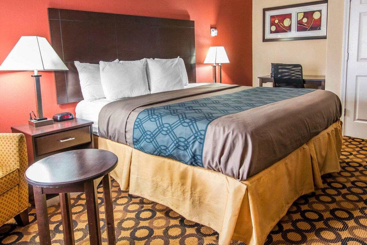 Een hotelkamer met een groot bed, twee bedlampen, een kleine tafel en een stoel.