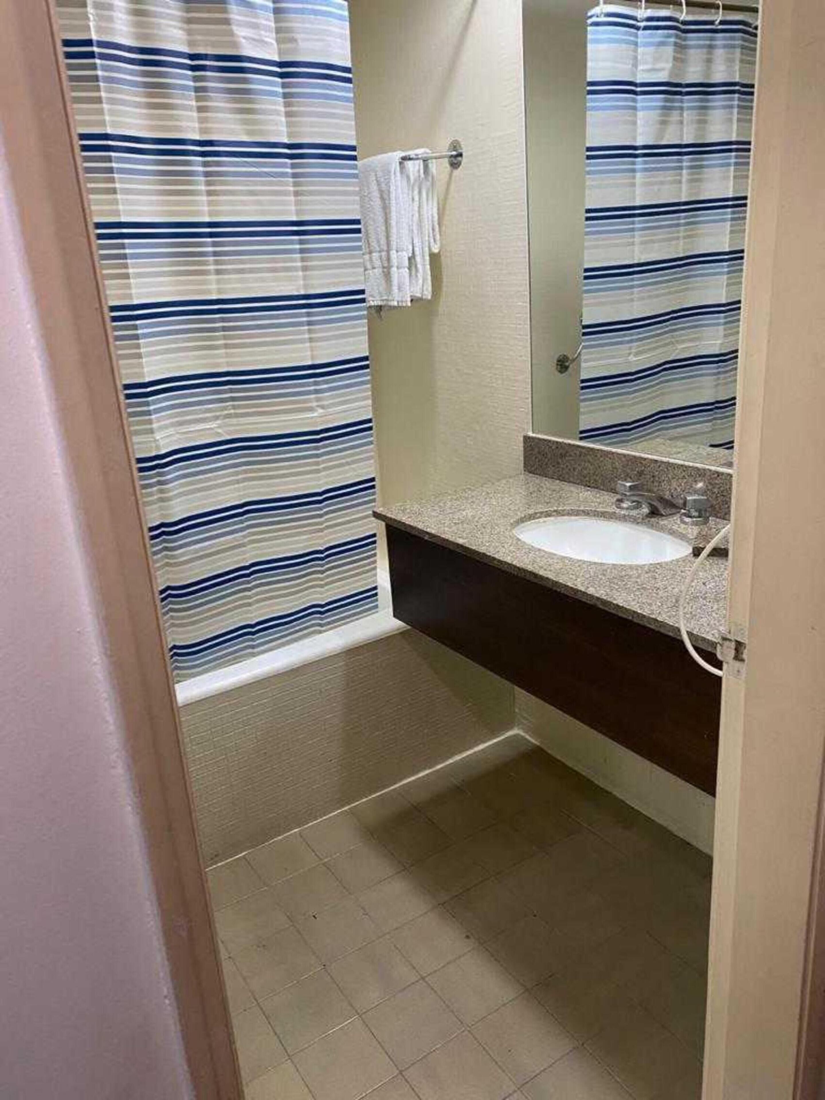 A bathroom with a striped shower curtain, a sink, and a mirror.