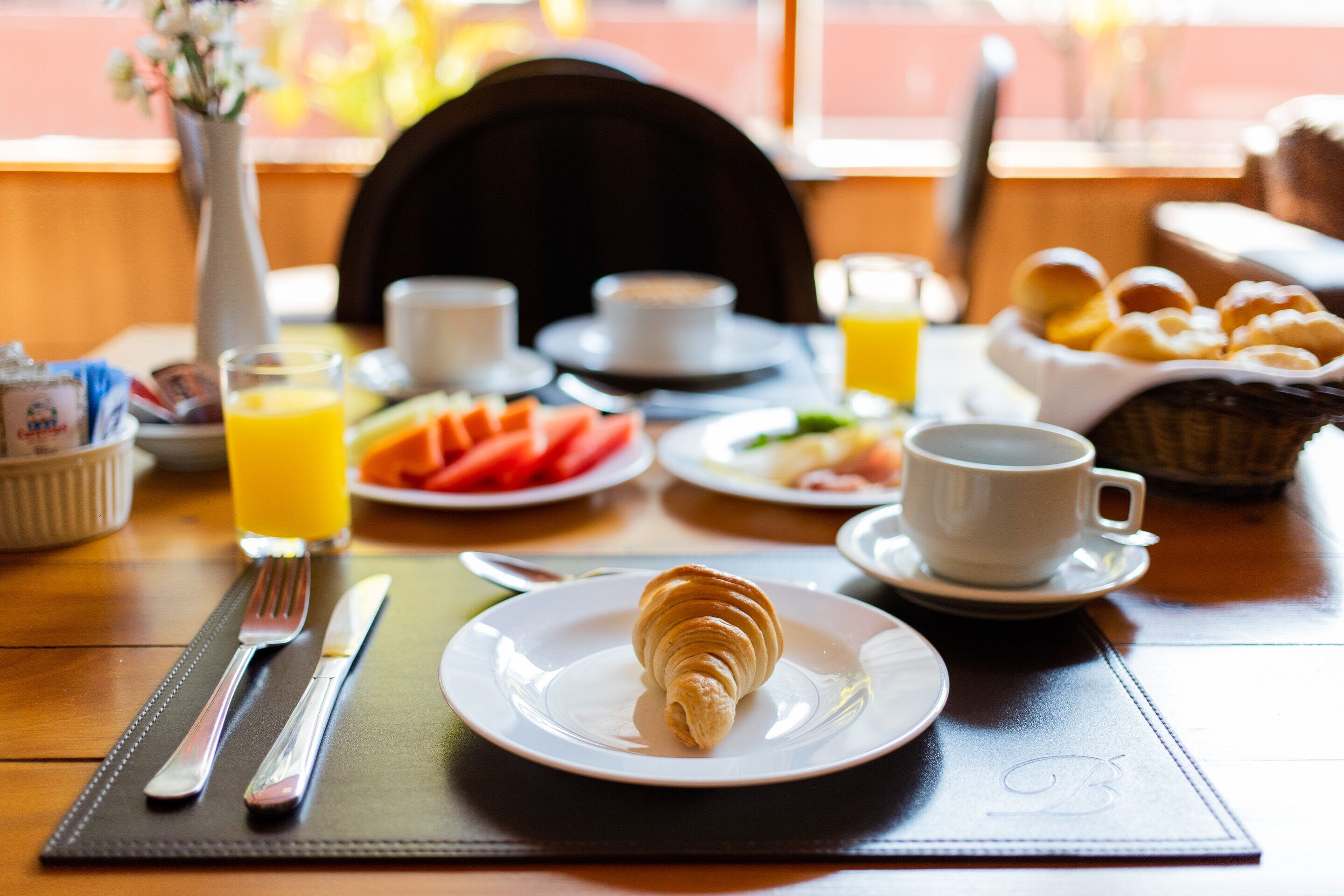 Colazione con croissant, succo d'arancia e una tazza di caffè su un tavolo.