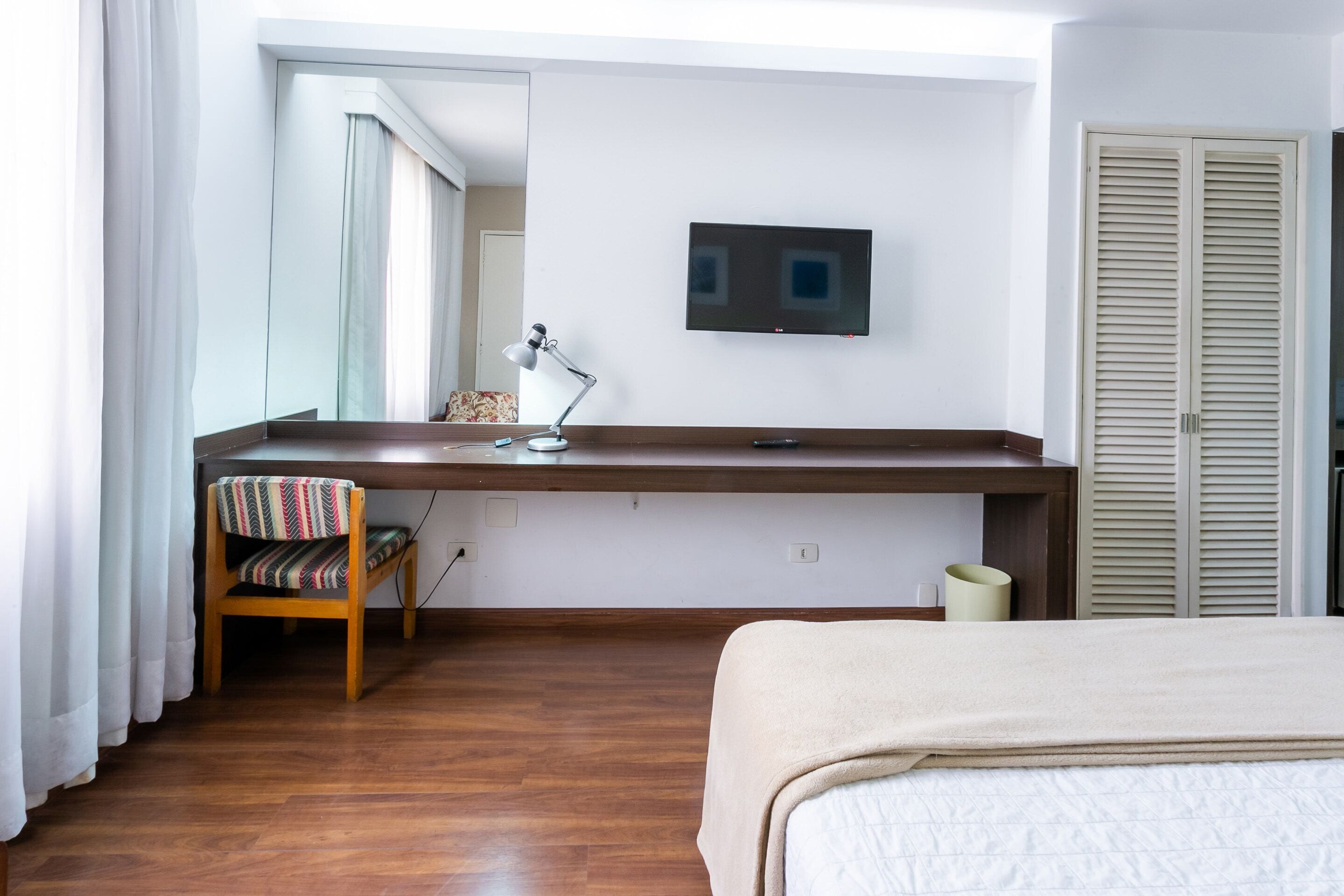 Ein Schlafzimmer mit einem Bett, einem Schreibtisch mit Stuhl, einem Fernseher und einem Kleiderschrank.