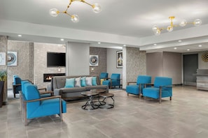 A modern lounge area with a sofa, armchairs, a coffee table, and a fireplace.