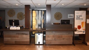 A reception desk with a digital screen, name tags, and a poster advertising local favorites. - Four Points by Sheraton Chicago Westchester/Oak Brook (Westchester)