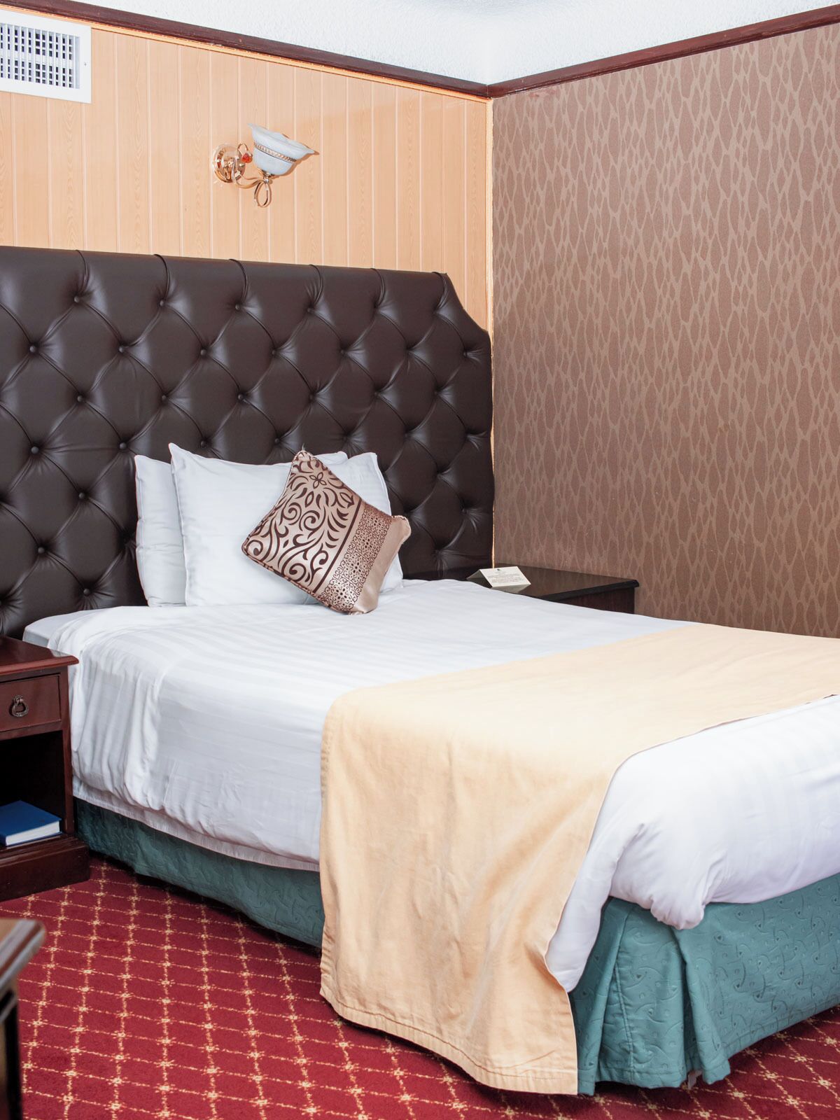 A neatly made bed with a tufted headboard, white bedding, and a beige throw blanket.