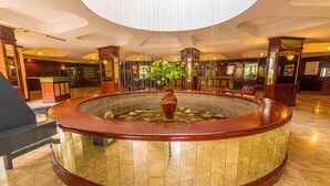 A lobby with a circular water feature, a reception desk, and a staircase. - Nairobi Safari Club by Swiss-Belhotel (Nairobi)