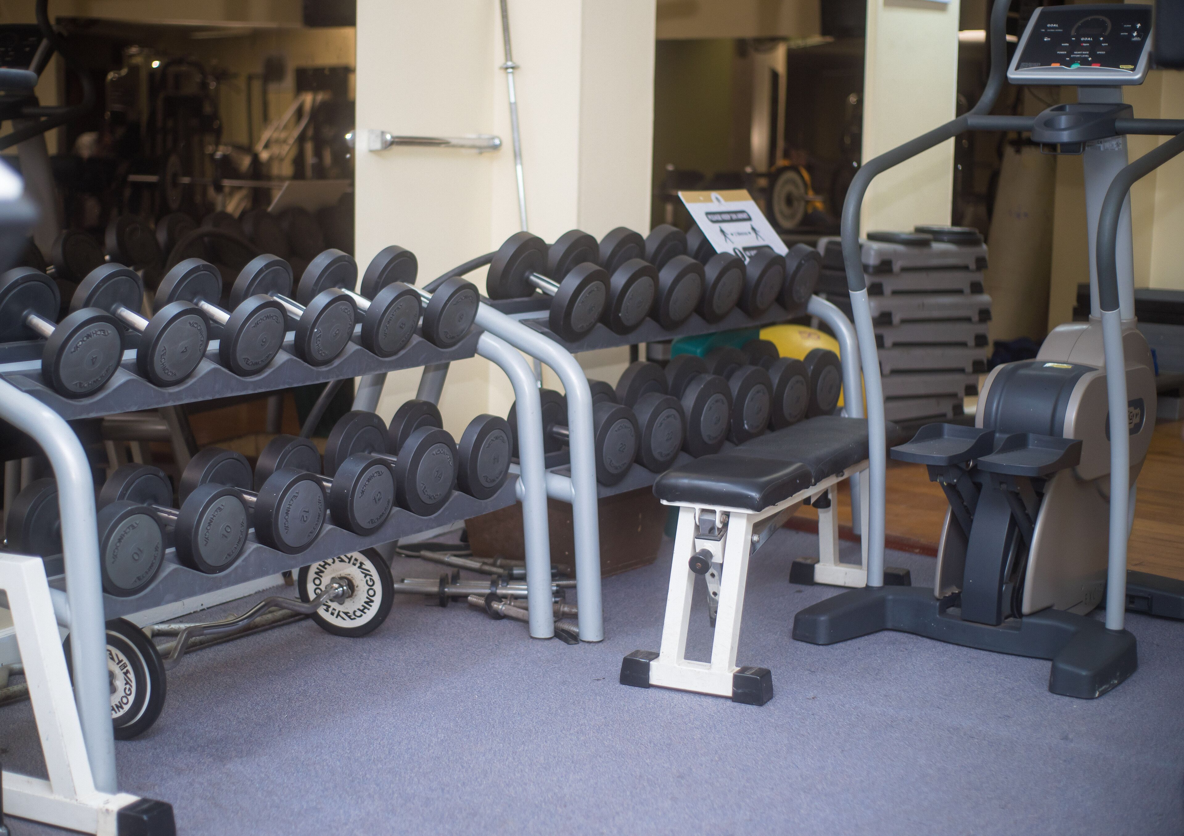 A gym with a bench, dumbbells, and exercise equipment.