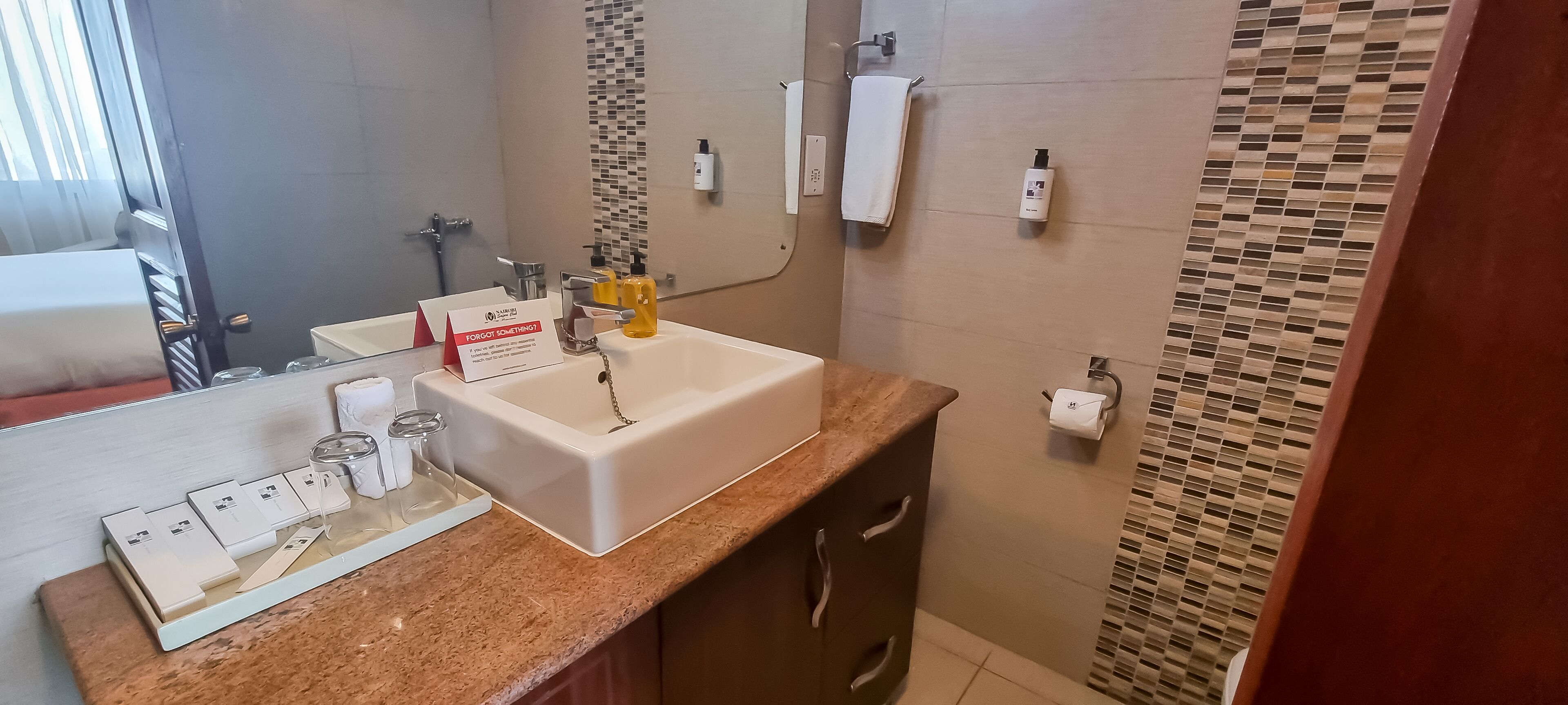 Une salle de bain moderne équipée d’un lavabo, d’un miroir, d’un porte-serviettes et d’articles de toilette.