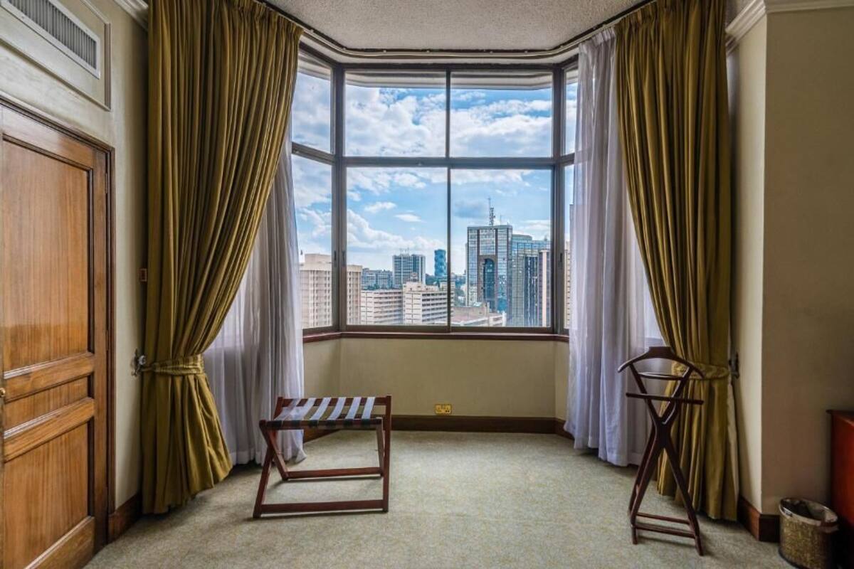 A corner room with a large window, a bench, and a coat rack.