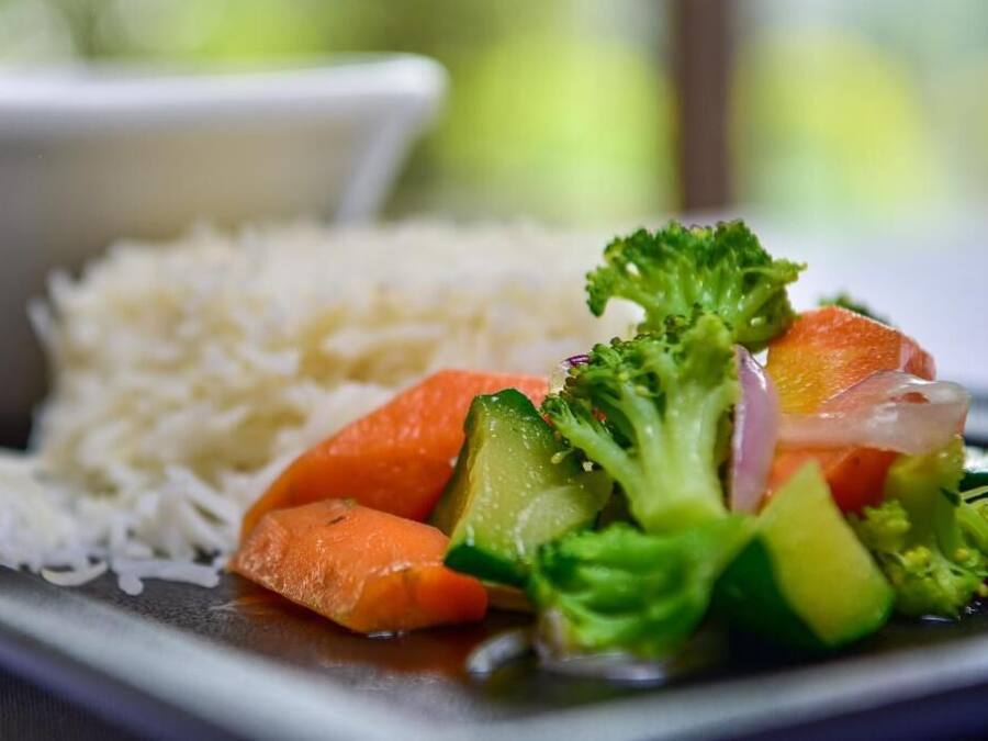 Un plato de arroz con salteado de verduras, incluyendo brócoli, zanahorias y cebollas.