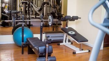 A gym with exercise equipment, a blue exercise ball, and a mirror reflecting the equipment.