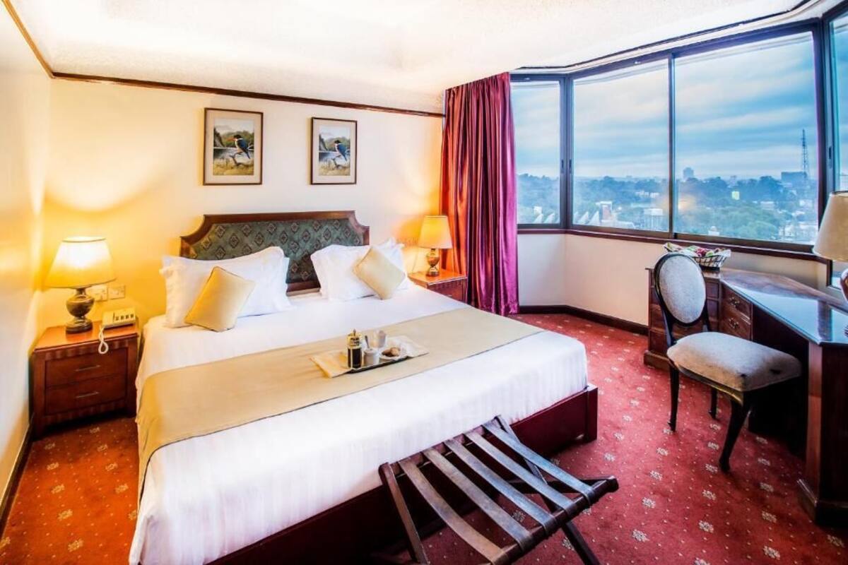 A hotel room with a large bed, a desk, and a view of the city.