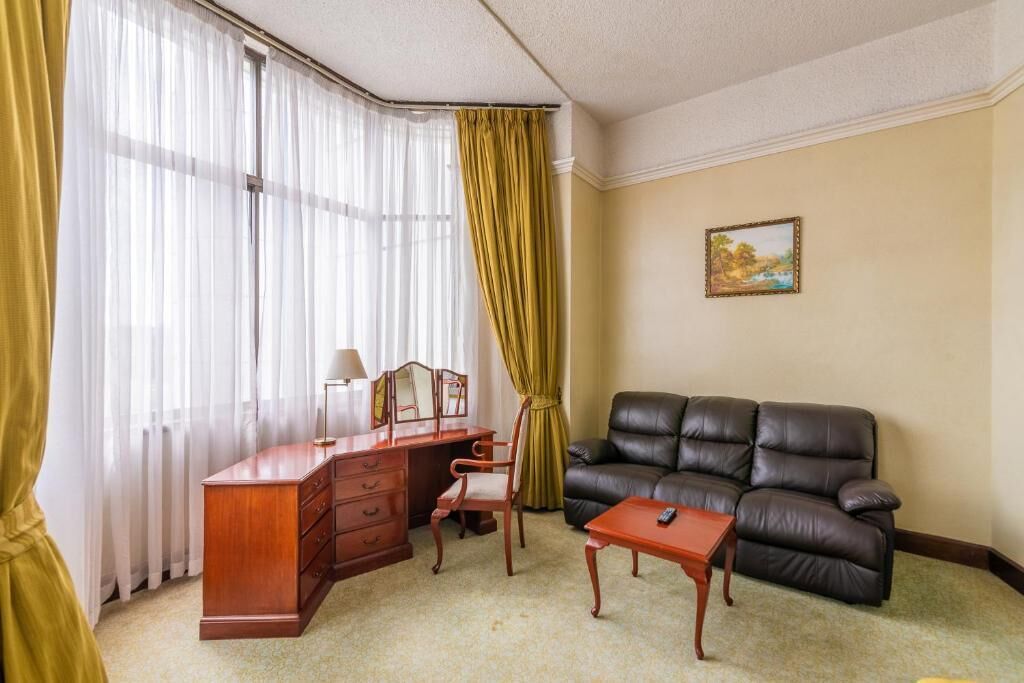 Une pièce comprenant un bureau, une chaise, un canapé en cuir et un tableau accroché au mur.