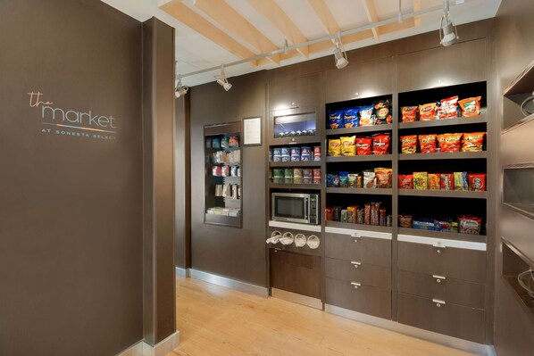 A kitchen area with shelves stocked with snacks and a microwave.