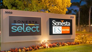 Un letrero de hotel con los logotipos 'SONESTA select' y 'Sonesta ES Suites', rodeado de un parterre floral.