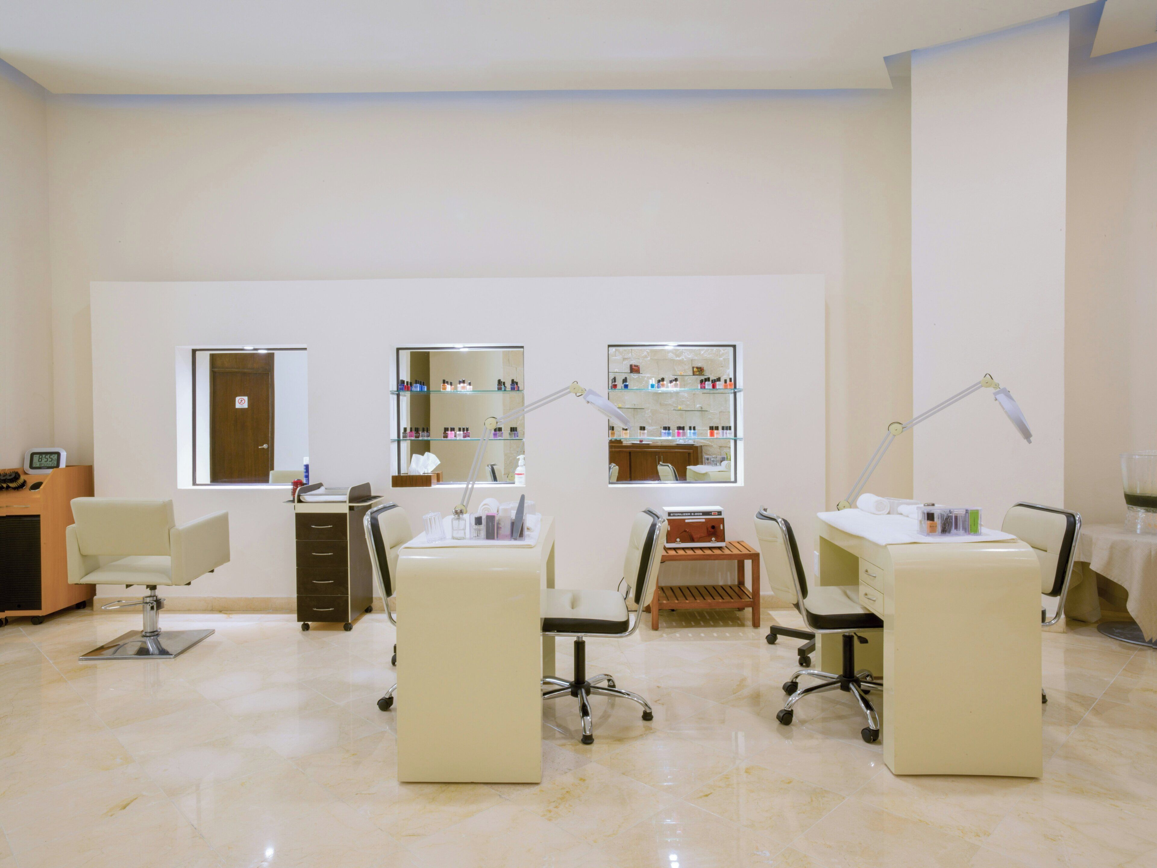 A clean, well-lit room with two desks, chairs, a mirror, and shelves with various items.
