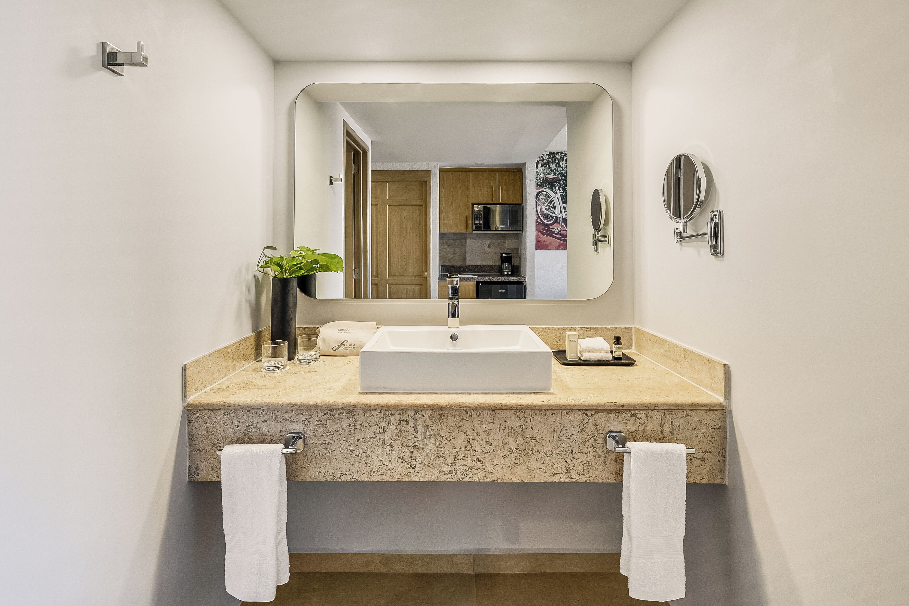 A modern bathroom with a large mirror, a sink, and a towel rack.