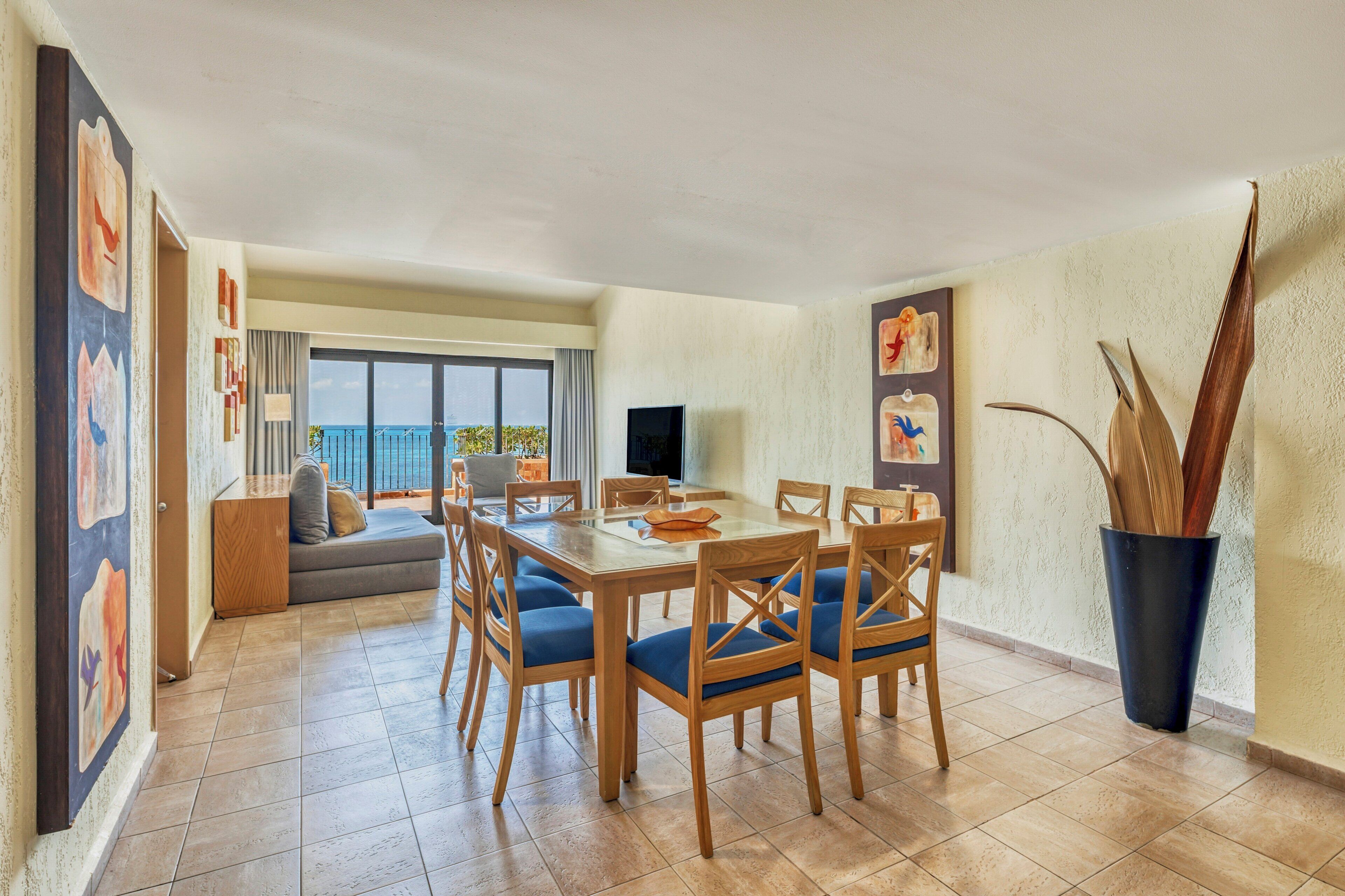 Un área de comedor con una mesa, sillas, un sofá y un televisor.
