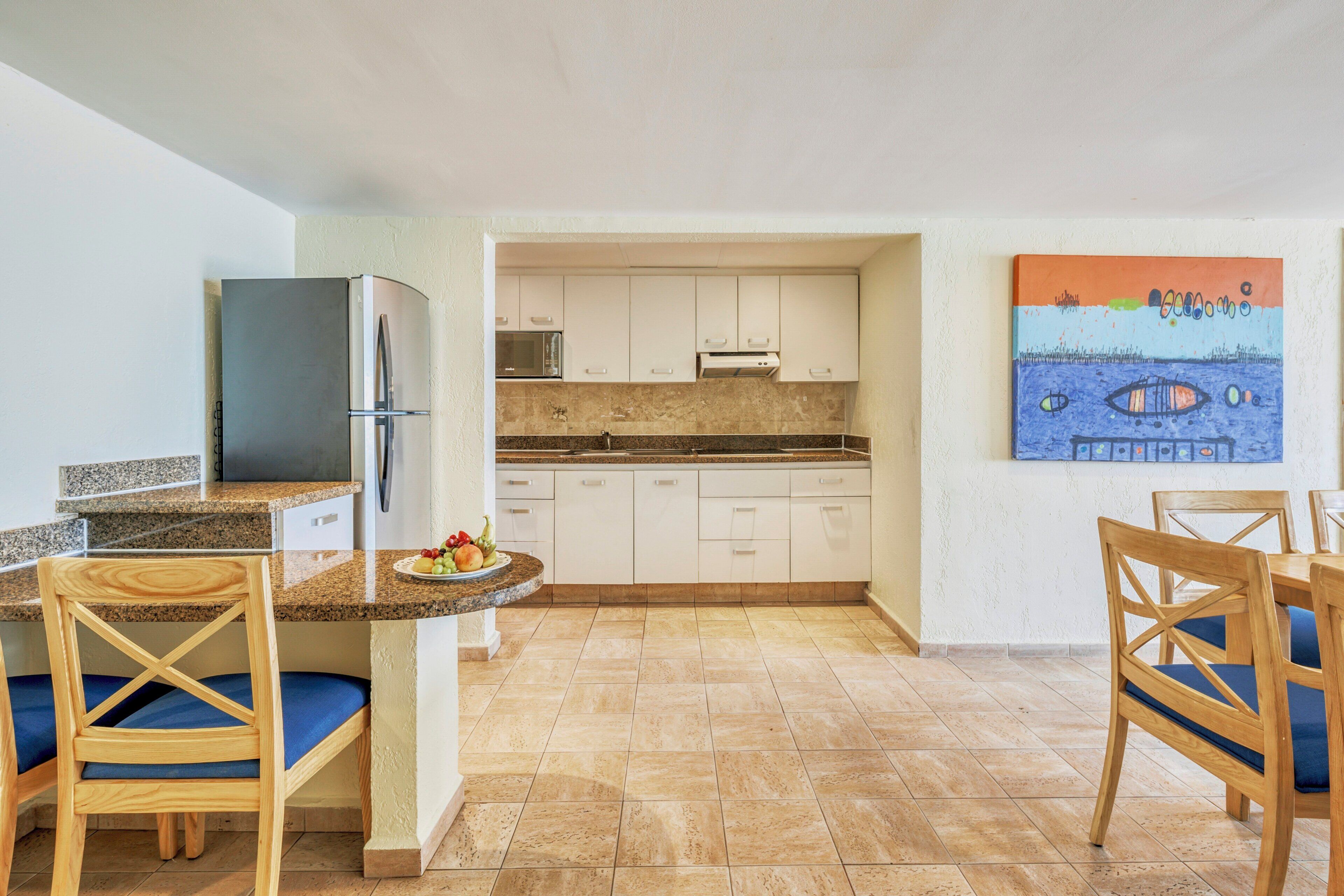 Une cuisine équipée d’un réfrigérateur, d’une cuisinière et d’un coin repas avec des chaises et une table.