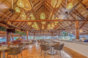 A restaurant with a thatched roof, multiple hanging light fixtures, and a view of the sea. - Fiesta Americana Cancun Villas (Cancun)