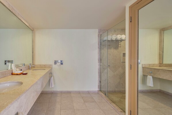 Un baño con un espejo grande, un lavabo, una cabina de ducha de vidrio y un perchero para toallas.