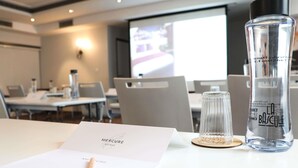 A conference room with a white table, a laptop, a bottle of La Pucelle perfume, and a Mercure hotel brochure. - Mercure Lyon Centre Charpennes Parc de la Tete d'Or (Villeurbanne)